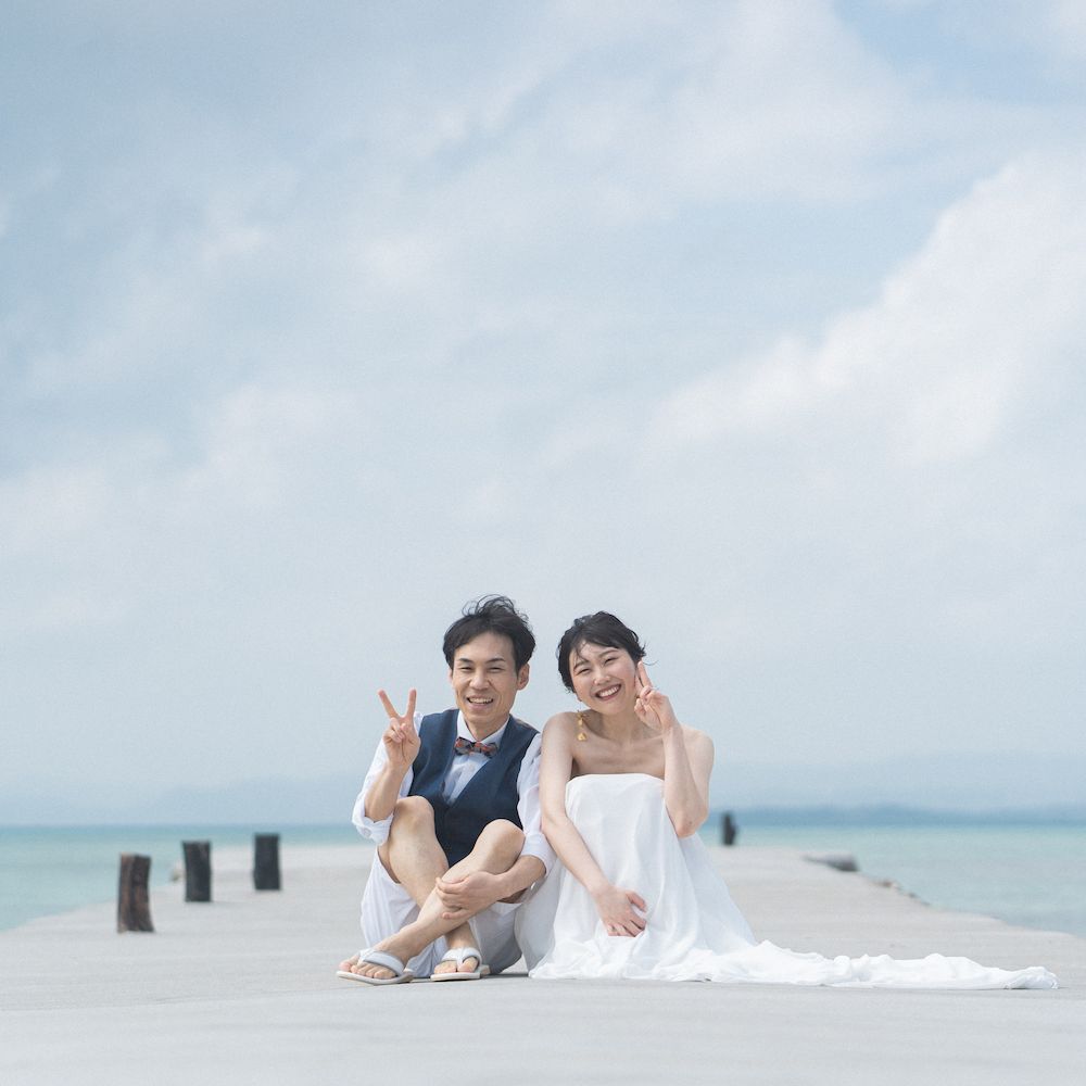 海を背景に堤防に立つ新郎新婦