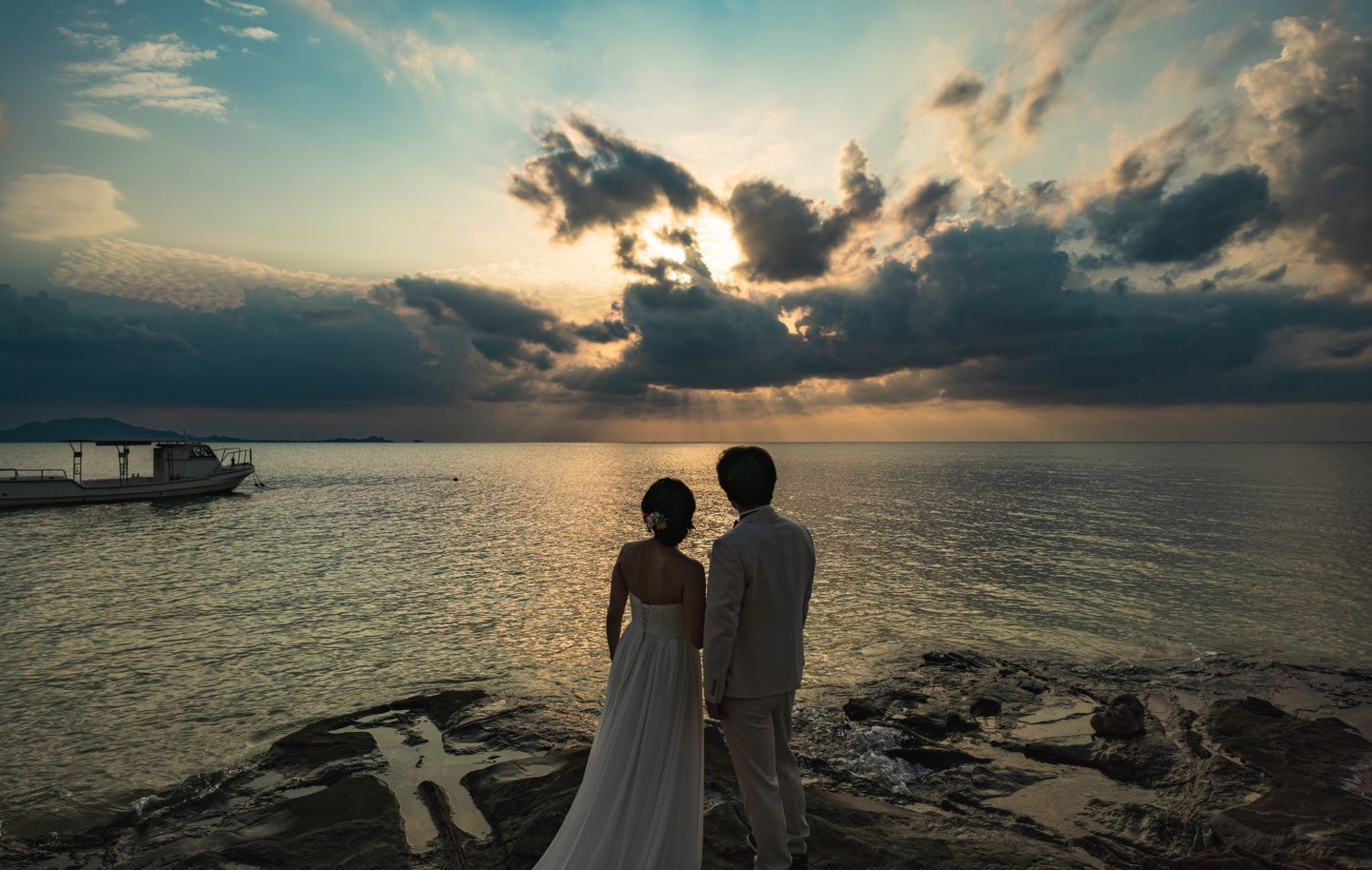 海を見渡す崖で肩を抱き合う新郎新婦の後ろ姿