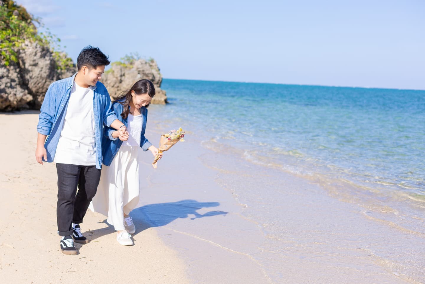 小浜島のビーチで浜辺を歩く新郎新婦