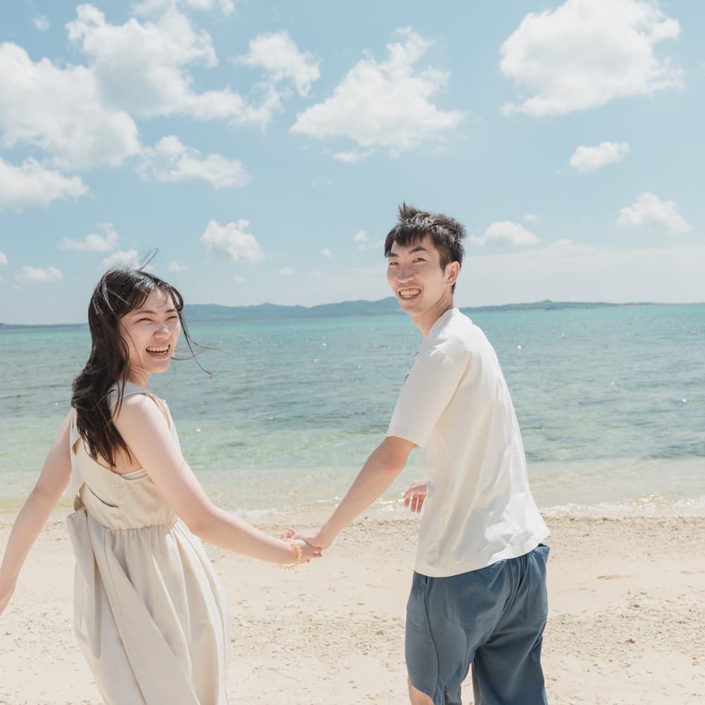 海を背景に手を繋いで振り返る新郎新婦