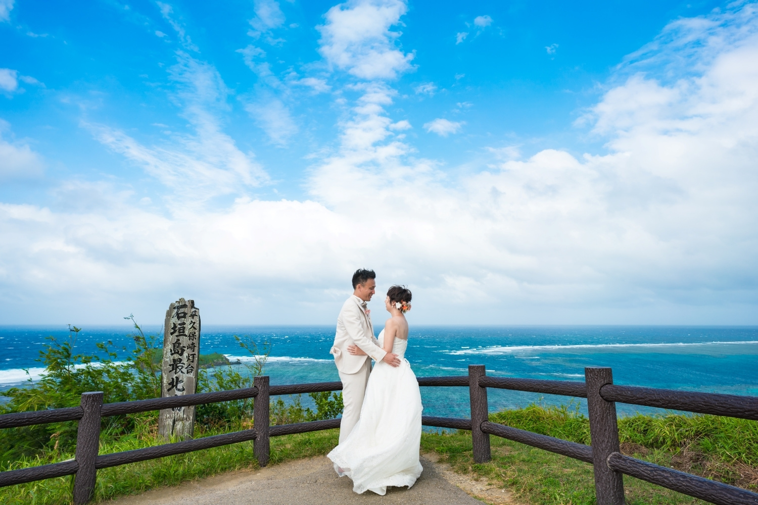 平久保崎灯台から見える青い海を背景に抱き合う新郎新婦