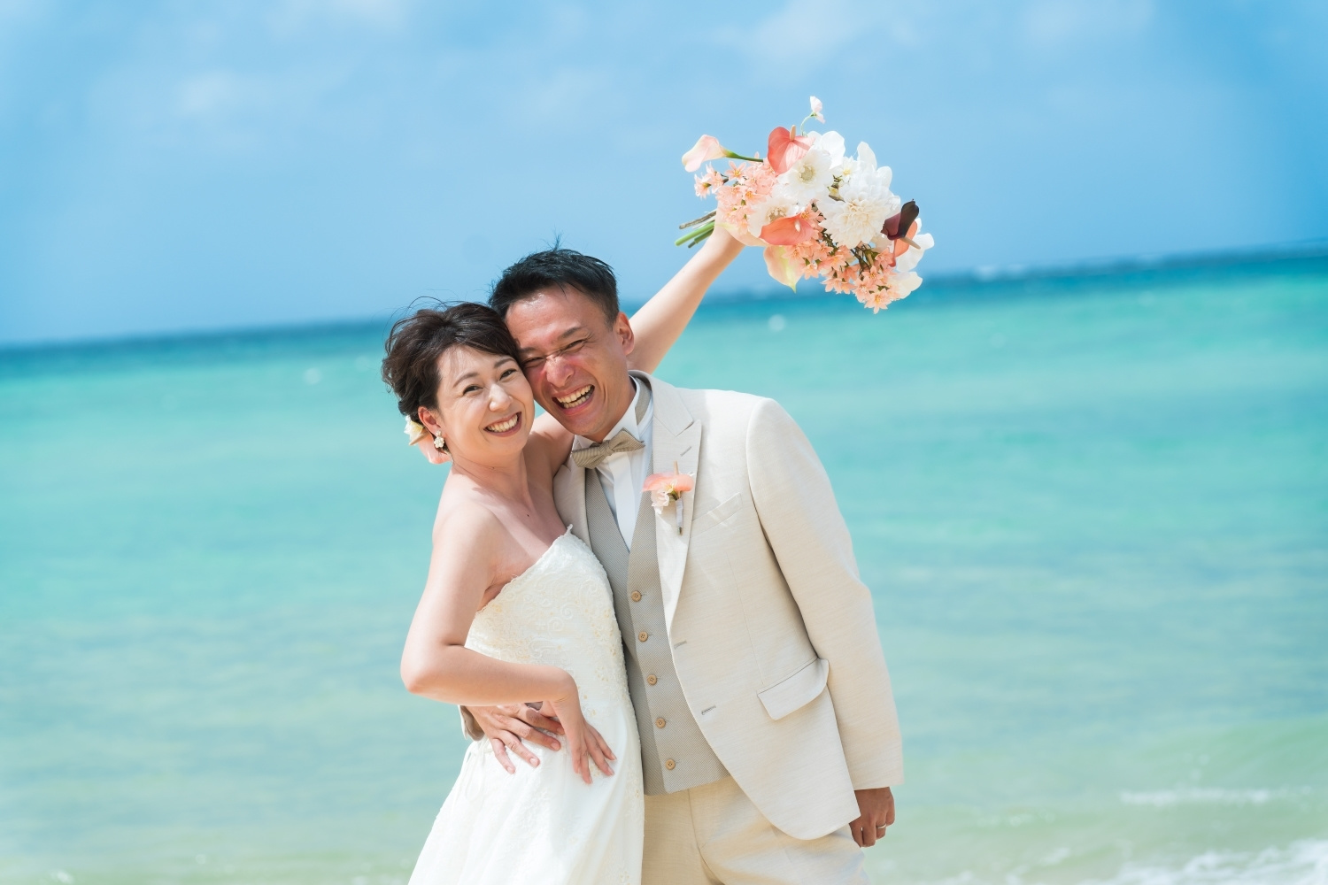 石垣島の青い海を背景にポーズをとる新郎新婦