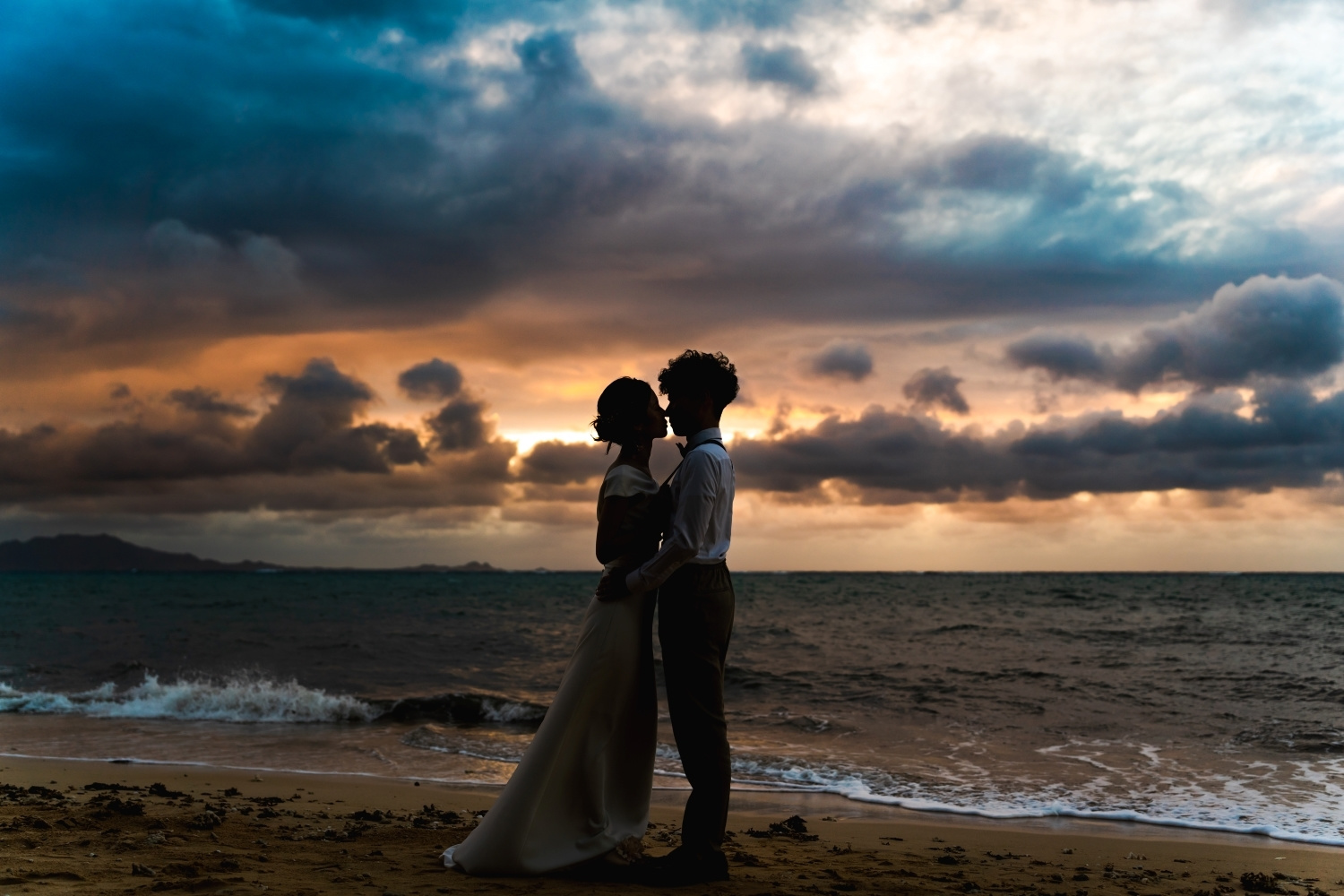 夕焼けに染まる海を背景に抱き合う新郎新婦