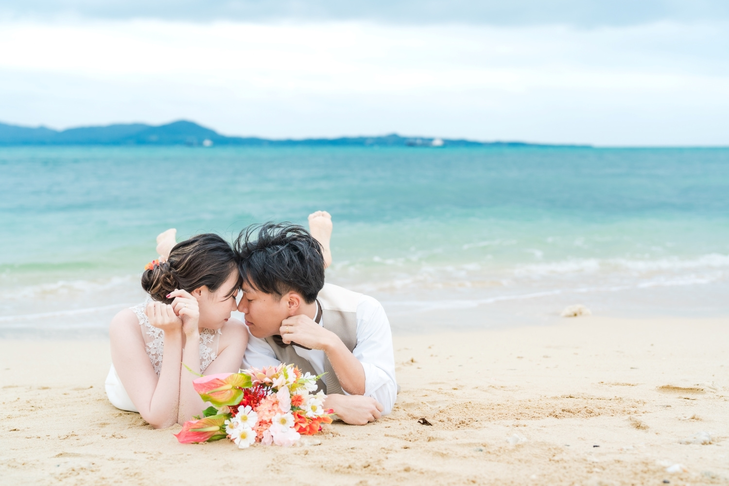波打ち際に寝そべる新郎新婦