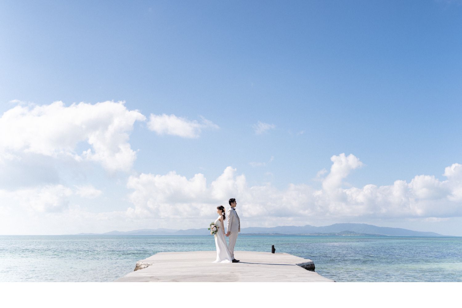 竹富島の西桟橋で背中合わせに立つ新郎新婦